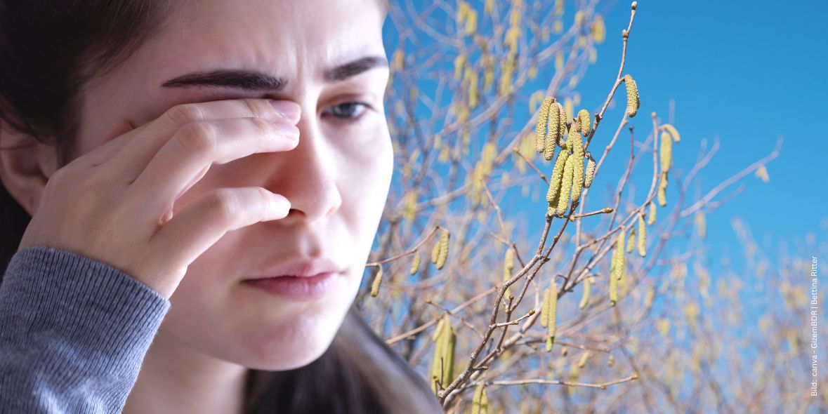 antiallergische-augentropfen-was-sind-antihistaminika Frau mit Allergie reibt sich die Augen im Hintergrund Haselpollen vor blauem Himmel zum Thema antiallergische Augentropfen - Was sind Antihistaminika